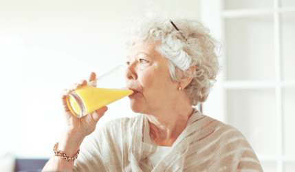 Older lady drinking a glass of orange juice to control her blood sugar